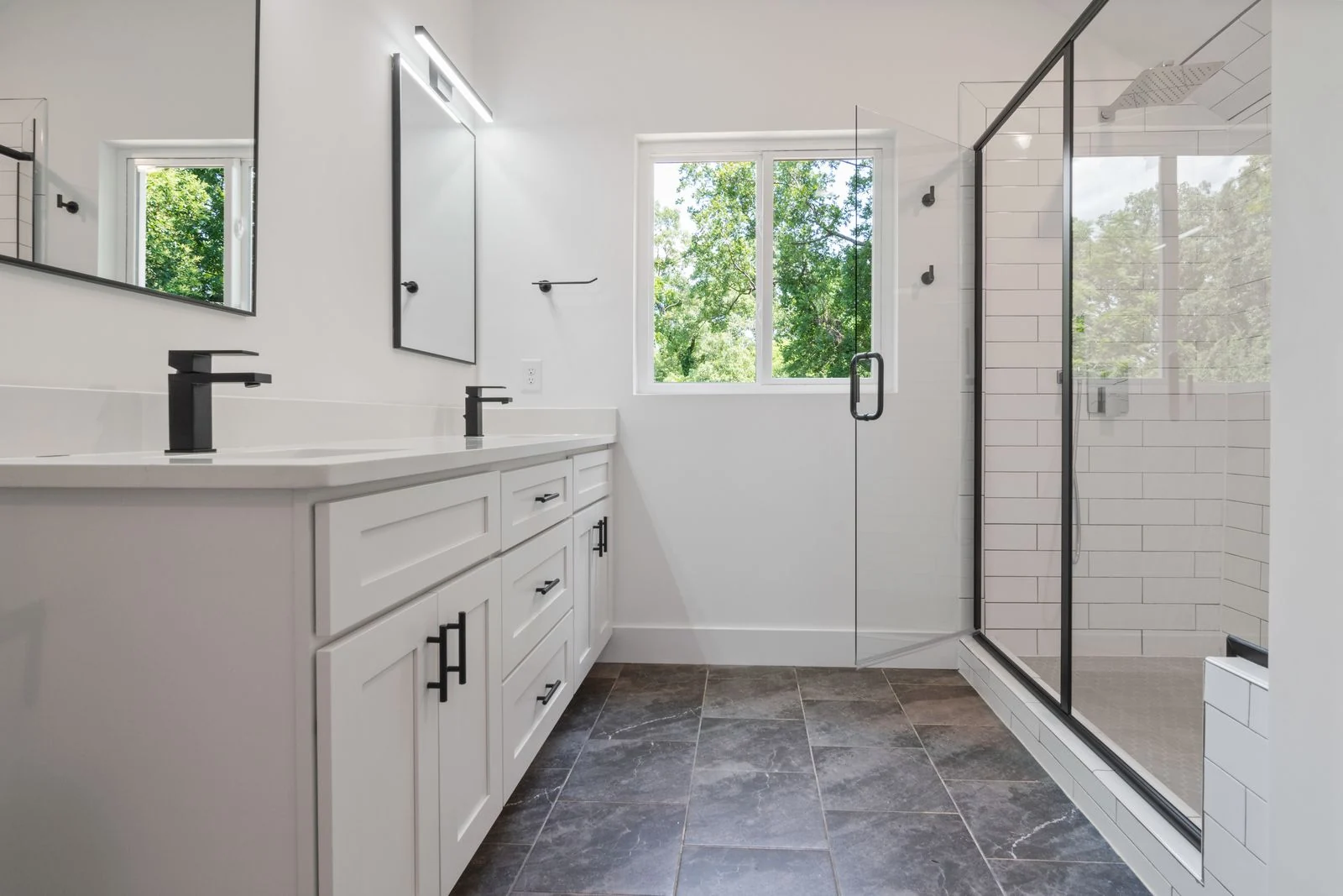 Elegant, sunlit bathroom featuring a glass-enclosed shower and sleek black fixtures for a modern touch